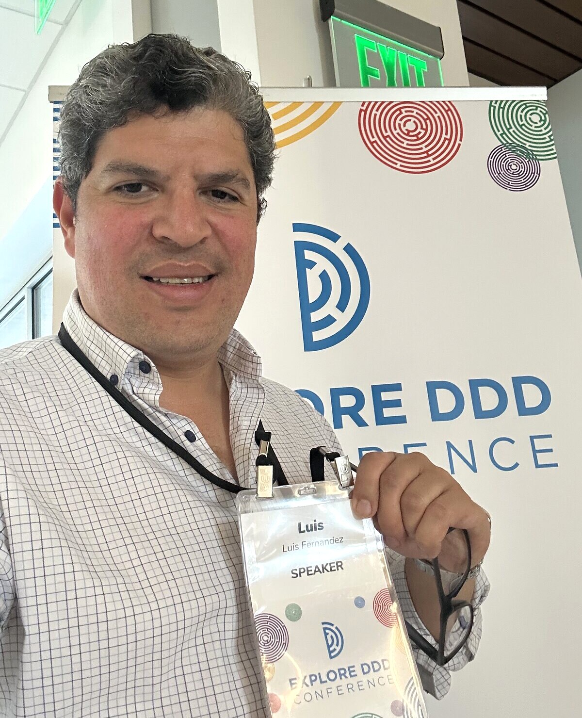 Luis Fernandez holding his speaker badge in front of the Explore DDD 2026 banner